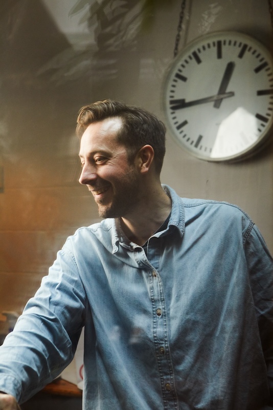 side head shot of singing teacher stood under a clock